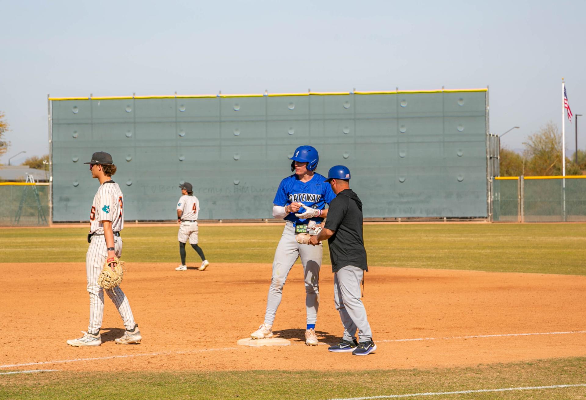 #3 for GateWay Matt Maize is talking to a coach on first base in a blue GateWay jersey 