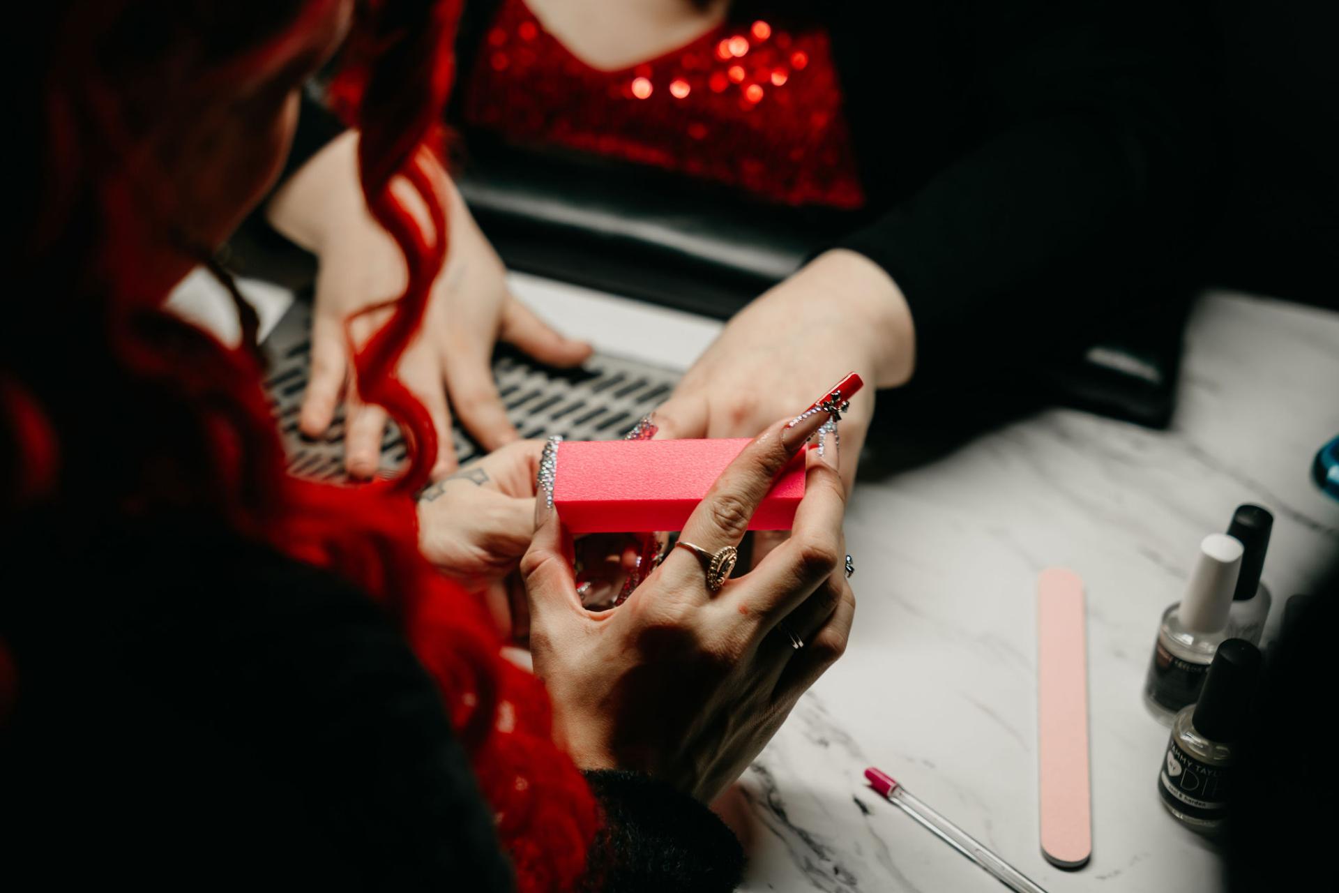 Close-up of a GateWay manicure session with a person filing another's nails using a pink nail file.