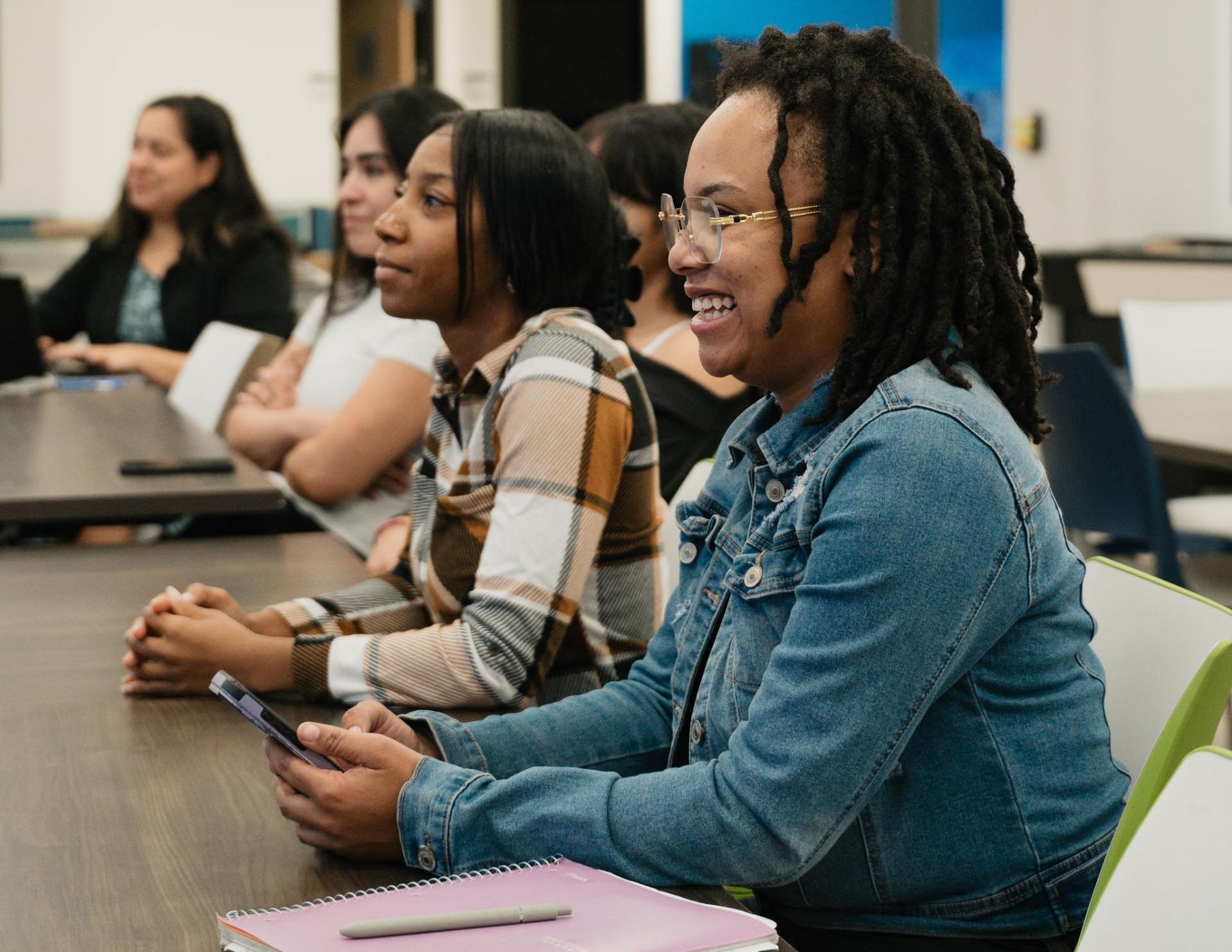 A student smiles as she listens to a lecture at GateWay Community College. The row has 3 more students engaged and listening beside her. 