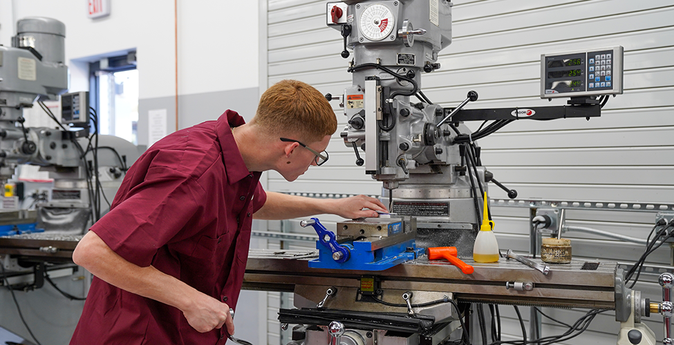 Male student working at large hand crank machine