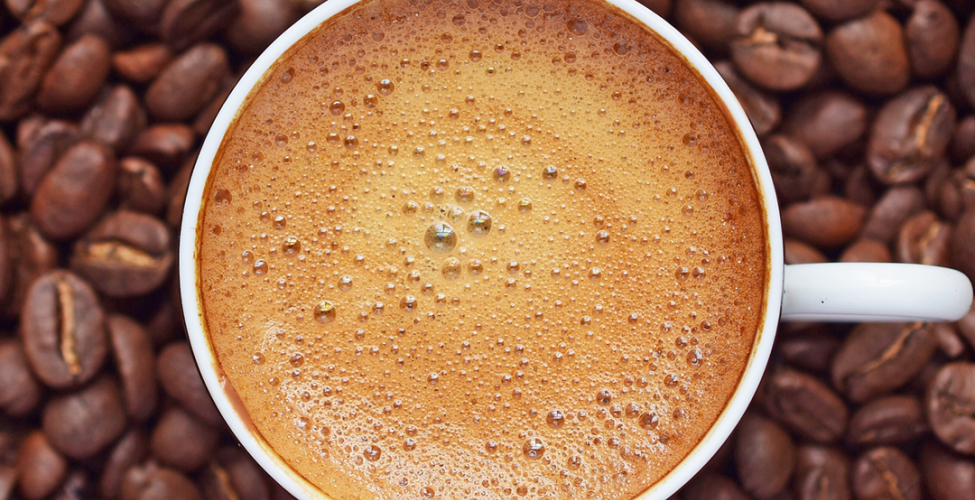 Coffee in a cup with brown beans surrounding the cup
