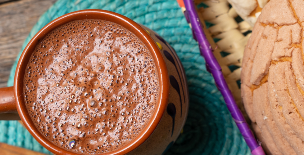 Mexican type of decorative insight with hot chocolate in a mug next to cinnamon sticks and mazapan in a basket 