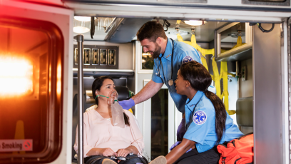 EMT responders caring for a patient wearing an oxygen mask inside an ambulance