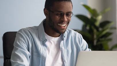 Male student sitting looking at a silver laptop 