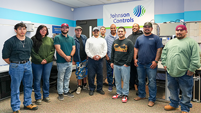 Group of diverse students standing in a classroom with banner with "Johnson Control" behind them