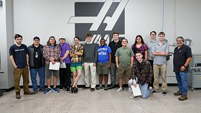 Group of machining students standing in front of grey wall