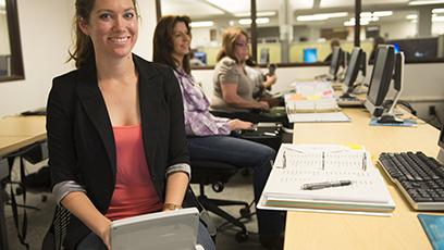 A smiling woman types at her steno machine in class