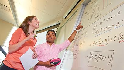Female teacher standing at whiteboard with males student