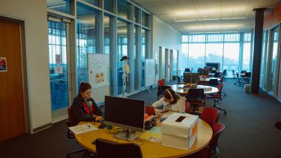 A brightly lit, window-lined academic workspace at GateWay Community College with two people working at a round table.
