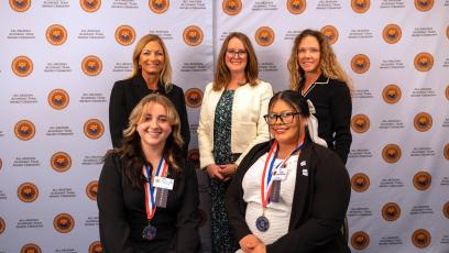 Students Samantha and Elisa take a photo with GateWay Community College President and faculty in front of a backdrop. 