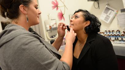 Woman applying makeup to a woman in chair