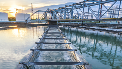 Water flowing outdoors through a water processing plant as the sun sets.