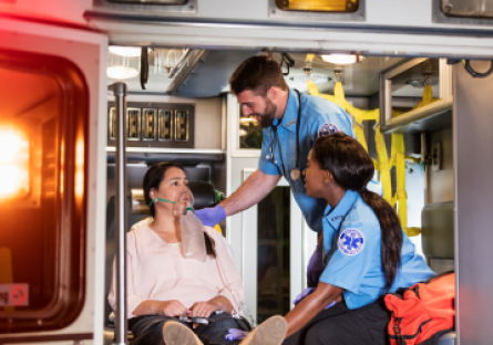 EMT responders caring for a patient wearing an oxygen mask inside an ambulance