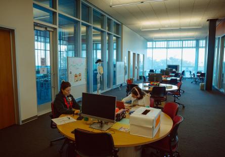 A brightly lit, window-lined academic workspace at GateWay Community College with two people working at a round table.