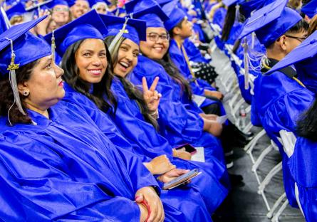 Students in blue caps and gown turn to the camera and smile during the GateWay 2025 Commencement Ceremony