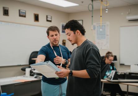 A student discusses a topic with his instructor in a healthcare class