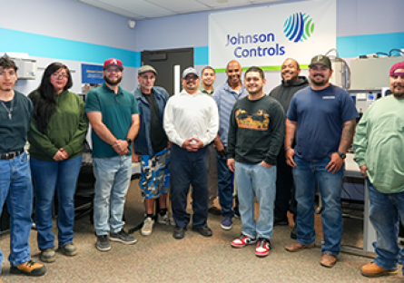 Group of diverse students standing in a classroom with banner with "Johnson Control" behind them