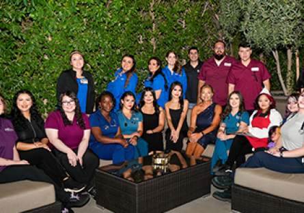 Group of students wearing scrubs sitting on an outdoor couch.