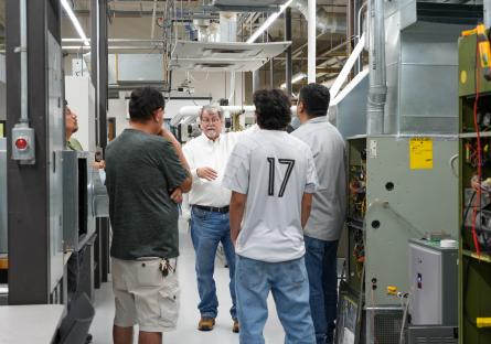 An HVAC instructor gives a tour of the GateWay HVAC lab to four potential students.