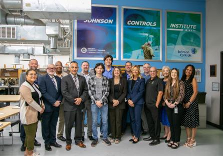 The group of students, JCI representatives, GateWay administration, and local leaders post in front of the new JCI sign in the HVAC lab. 
