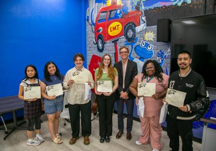 Students gather with their certificates after reading their writing submissions