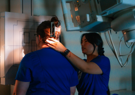 Two GateWay radiology students in blue scrubs work in the lab during class. 