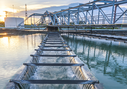 Water flowing outdoors through a water processing plant as the sun sets.