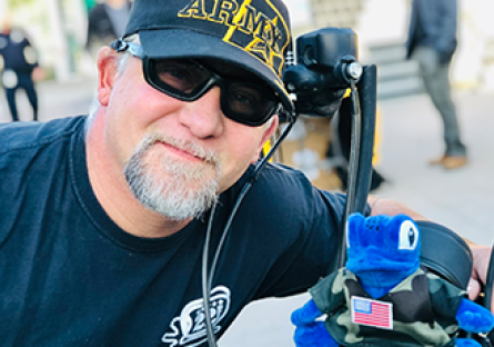 Dr. Joseph Swaba poses with a plush Echo the Gecko sitting on the front of his motorcycle.