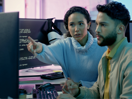 Image of woman and man sitting in front of two computer monitors