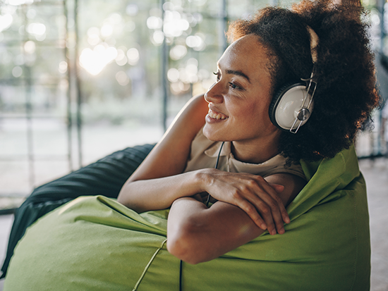 Female wearing white headphones laying on a green bag