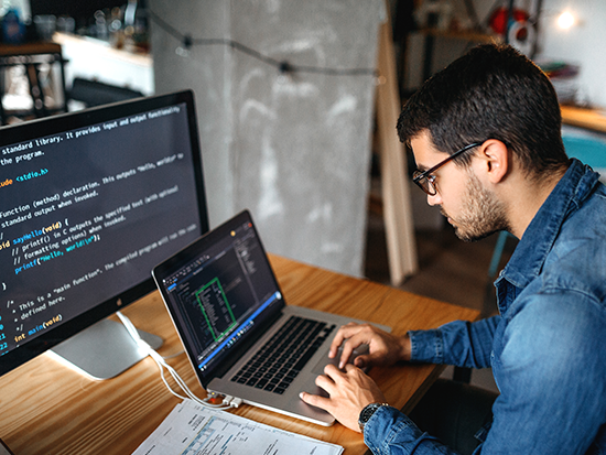 Man sitting at desk looking at laptop