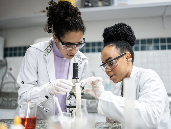 Two female students looking at microscope