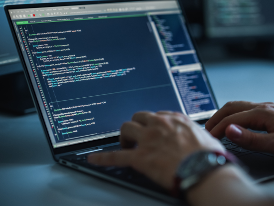 Code on a computer screen with hands typing on the keyboard