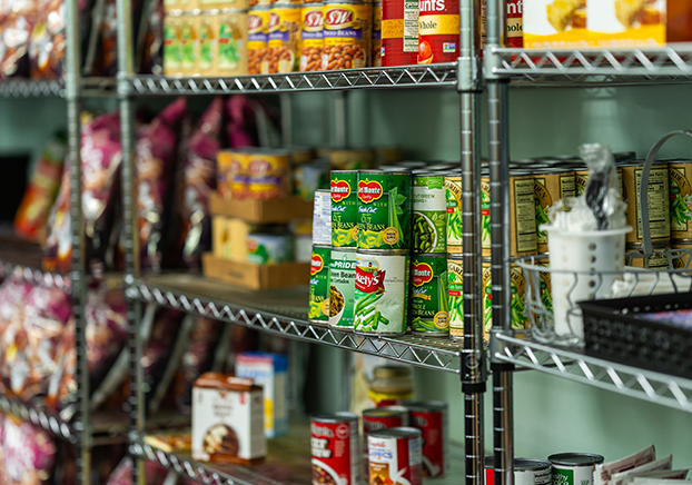 Shelves stocked with canned goods, boxed food, and packaged snacks inside a food pantry.