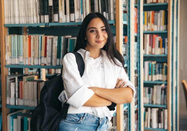 Student with a backpack leaning against a bookshelf