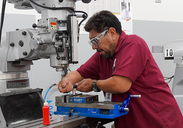 Male students with a wrench workin on a hand crack machining tool