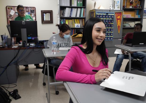 Student writing on a mini whiteboard during class in a learning center.