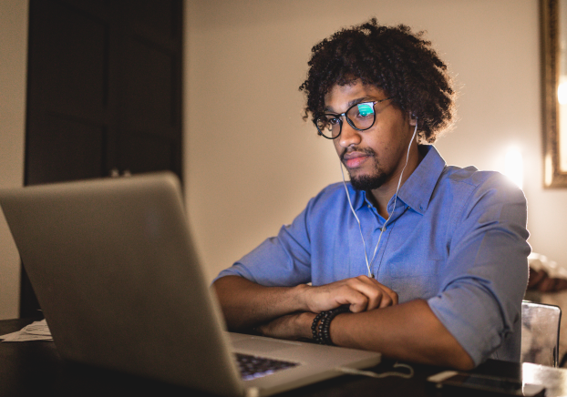 Male student looking at silver laptop computer