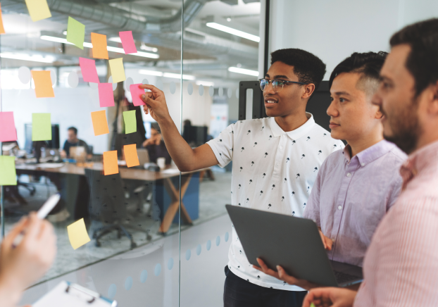 Group of individuals look at board with sticky notes