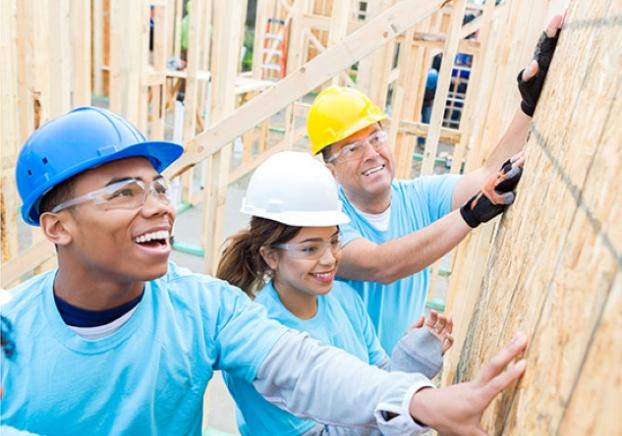 Constructions workers wearing hard hats while on the jobsite installing a wall