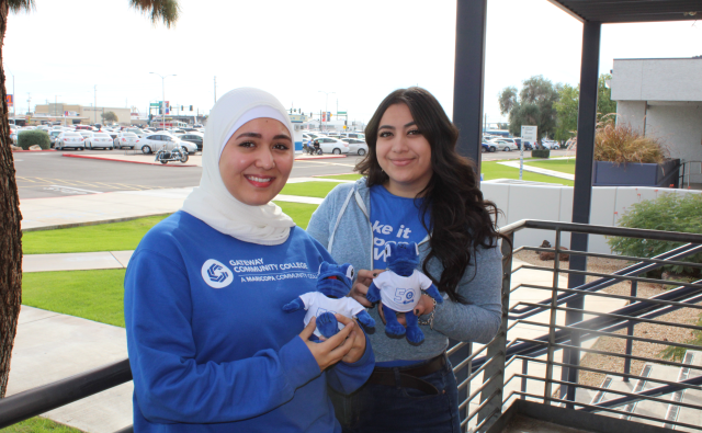 2 students outside taking a picture with GateWay mascot plushie