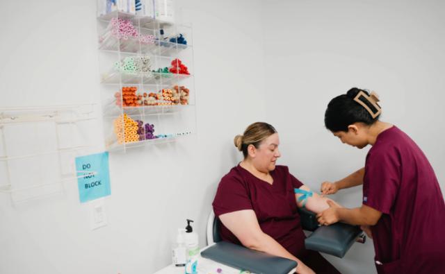 Phlebotomy student performing arm preparation for a blood draw