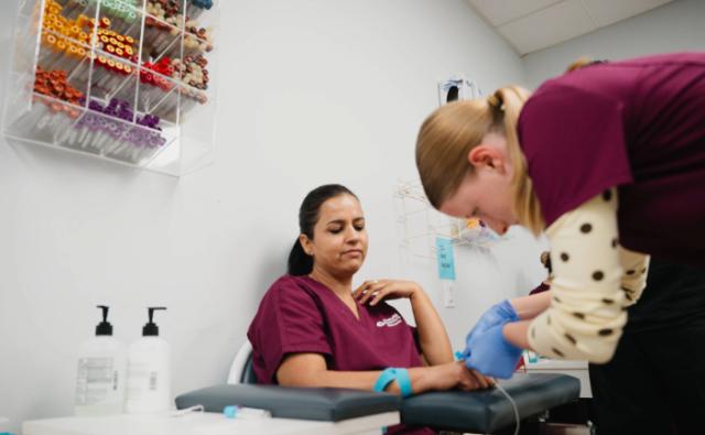 Student practicing blood collection techniques on a patient in a phlebotomy room