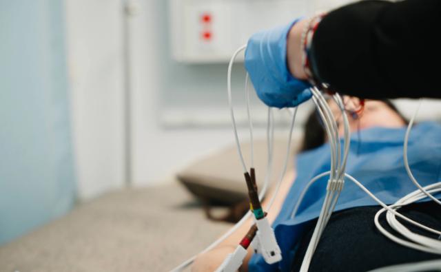 Healthcare provider preparing ECG lead cables beside a patient bed