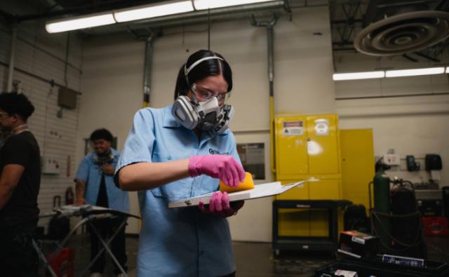 Collision repair student mixing body filler with protective gear