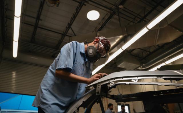 Student inspecting an auto frame section in a collision repair shop