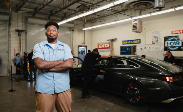 Automotive collision repair student standing in the training garage